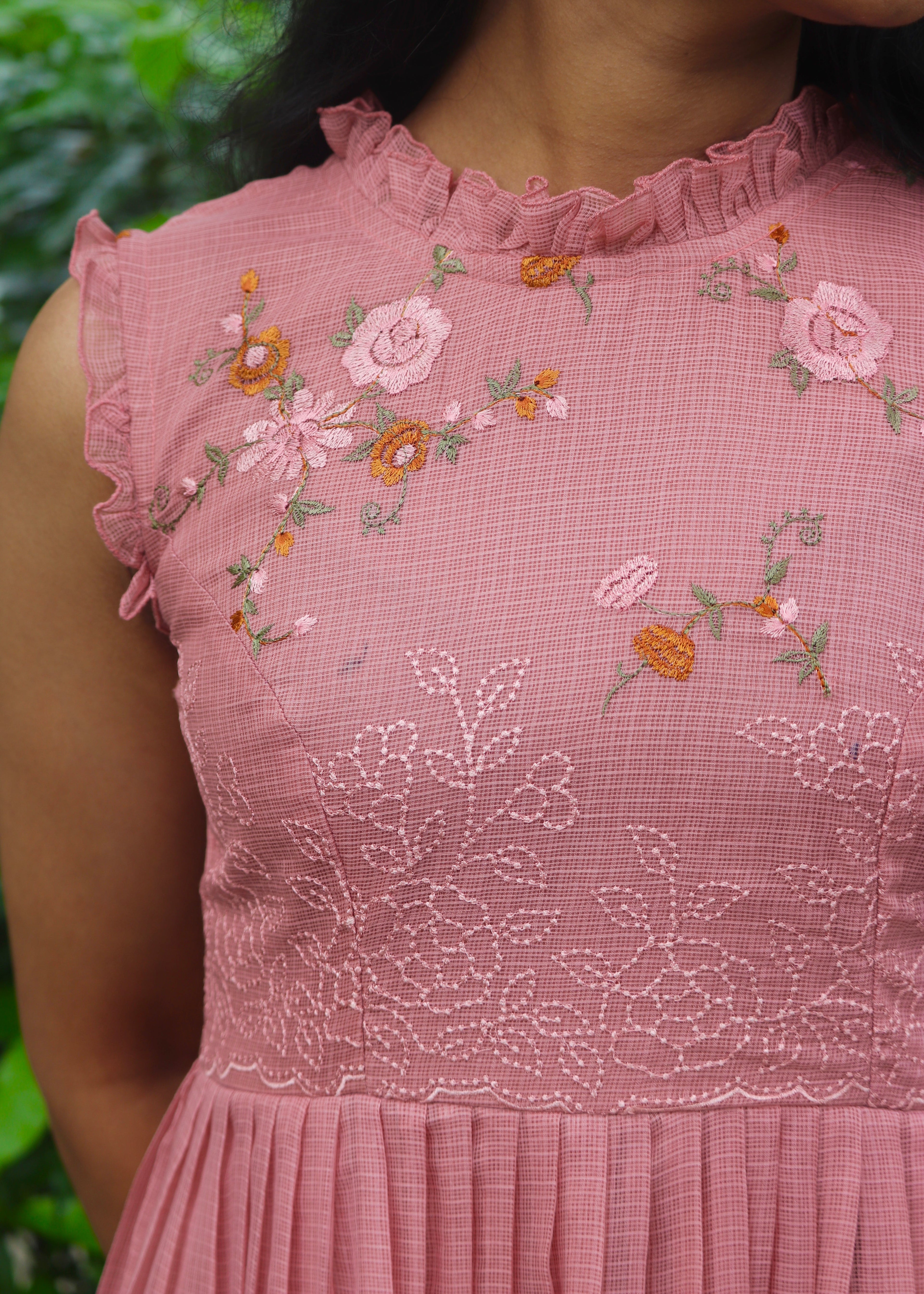Close-up of a pink dress with floral embroidery against a blurred green background