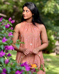 Woman in a pink dress standing among flowers and greenery