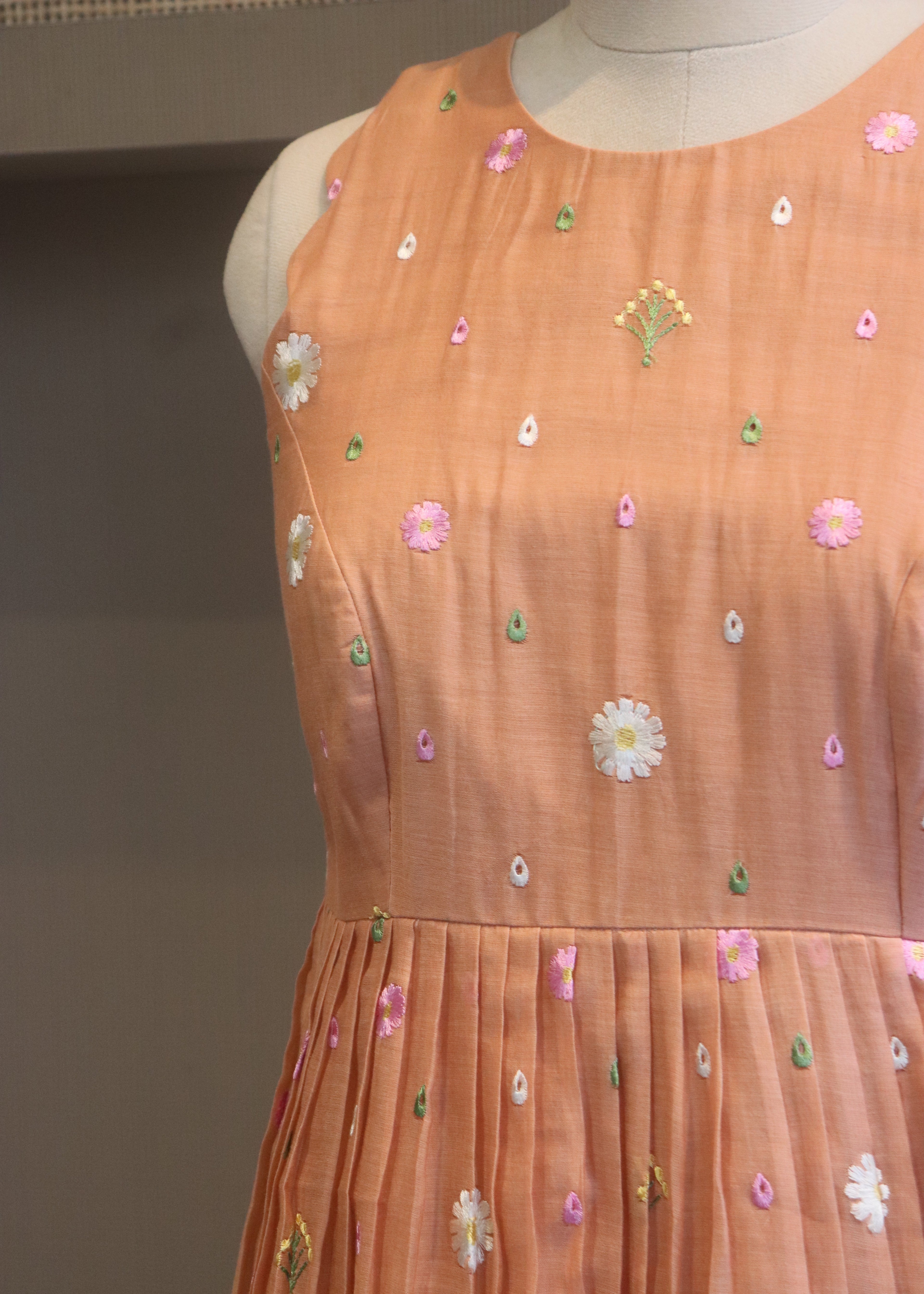 Close-up of a peach-colored fabric with floral embroidery on a neutral background