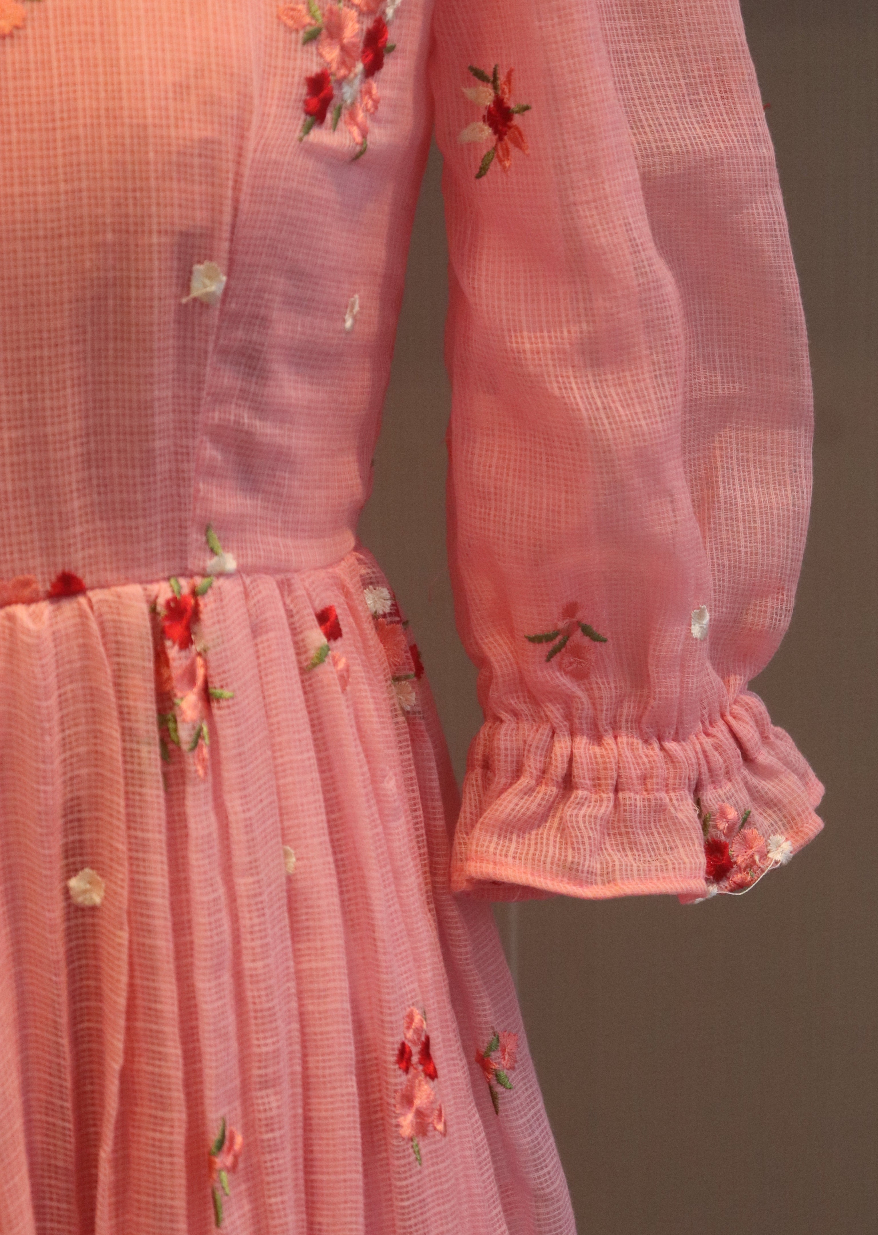 Close-up of a pink garment with floral embroidery on a dark background