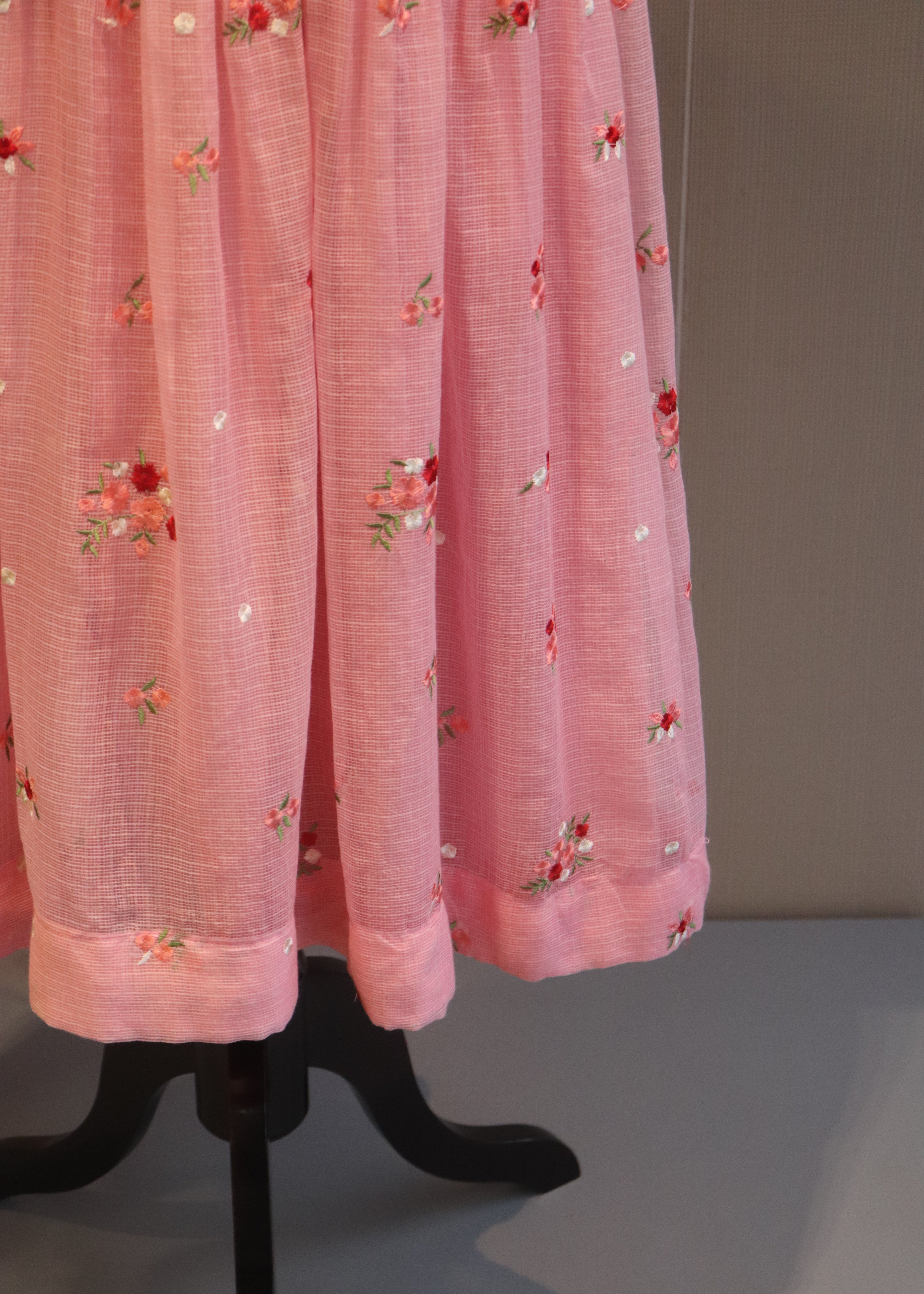 Pink dress with floral embroidery on a gray background