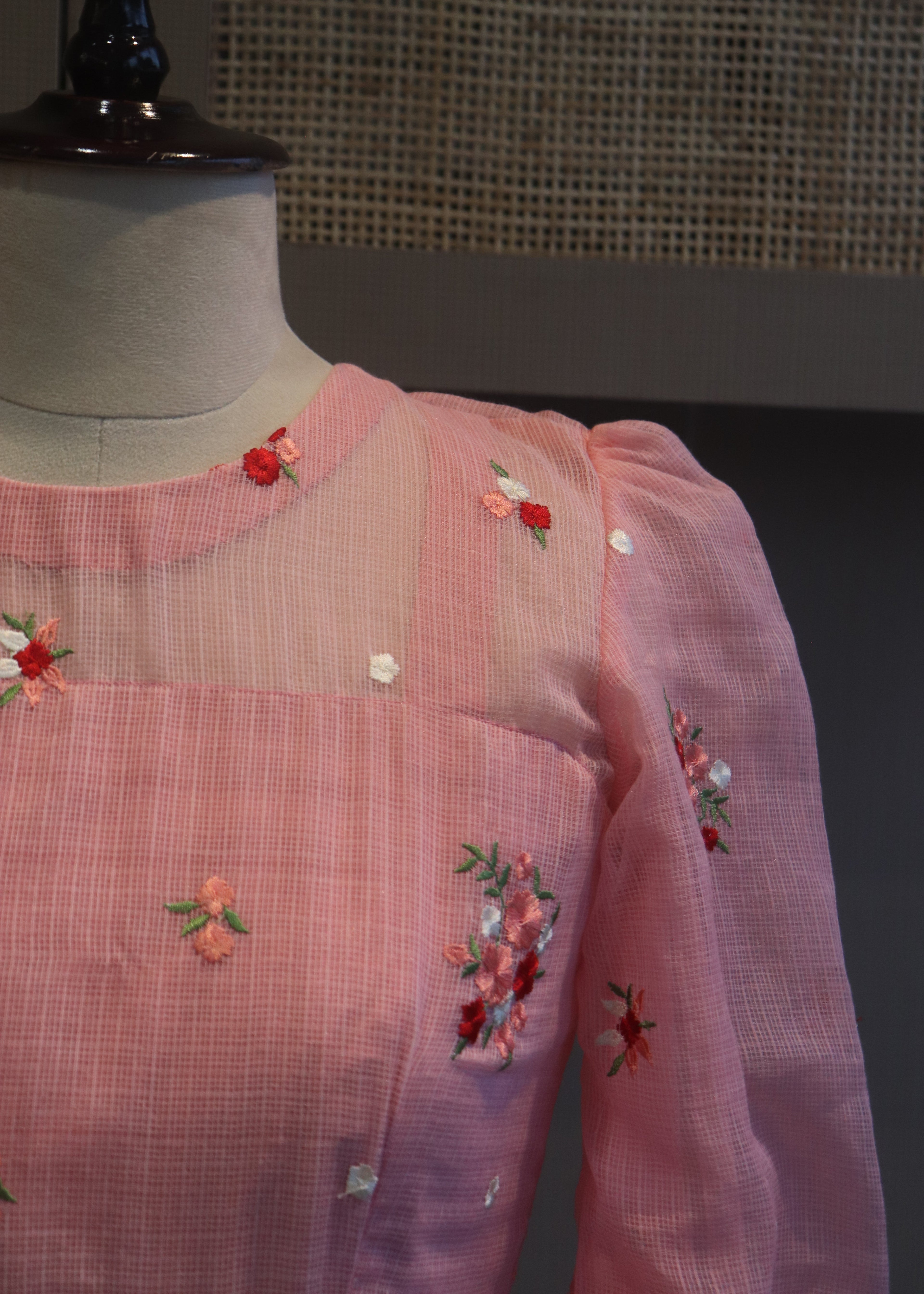 Pink embroidered blouse on a dark surface