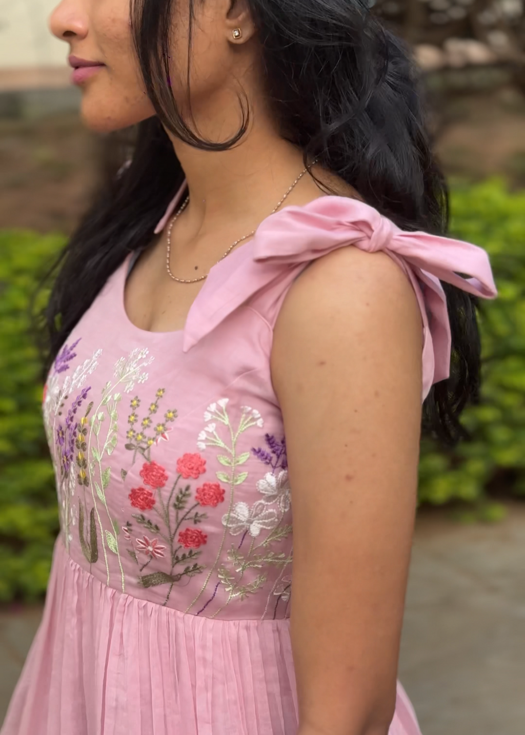 Woman wearing a pink dress with floral embroidery outdoors