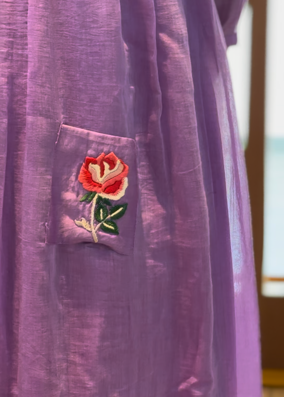 Purple fabric with a floral embroidery on a pocket