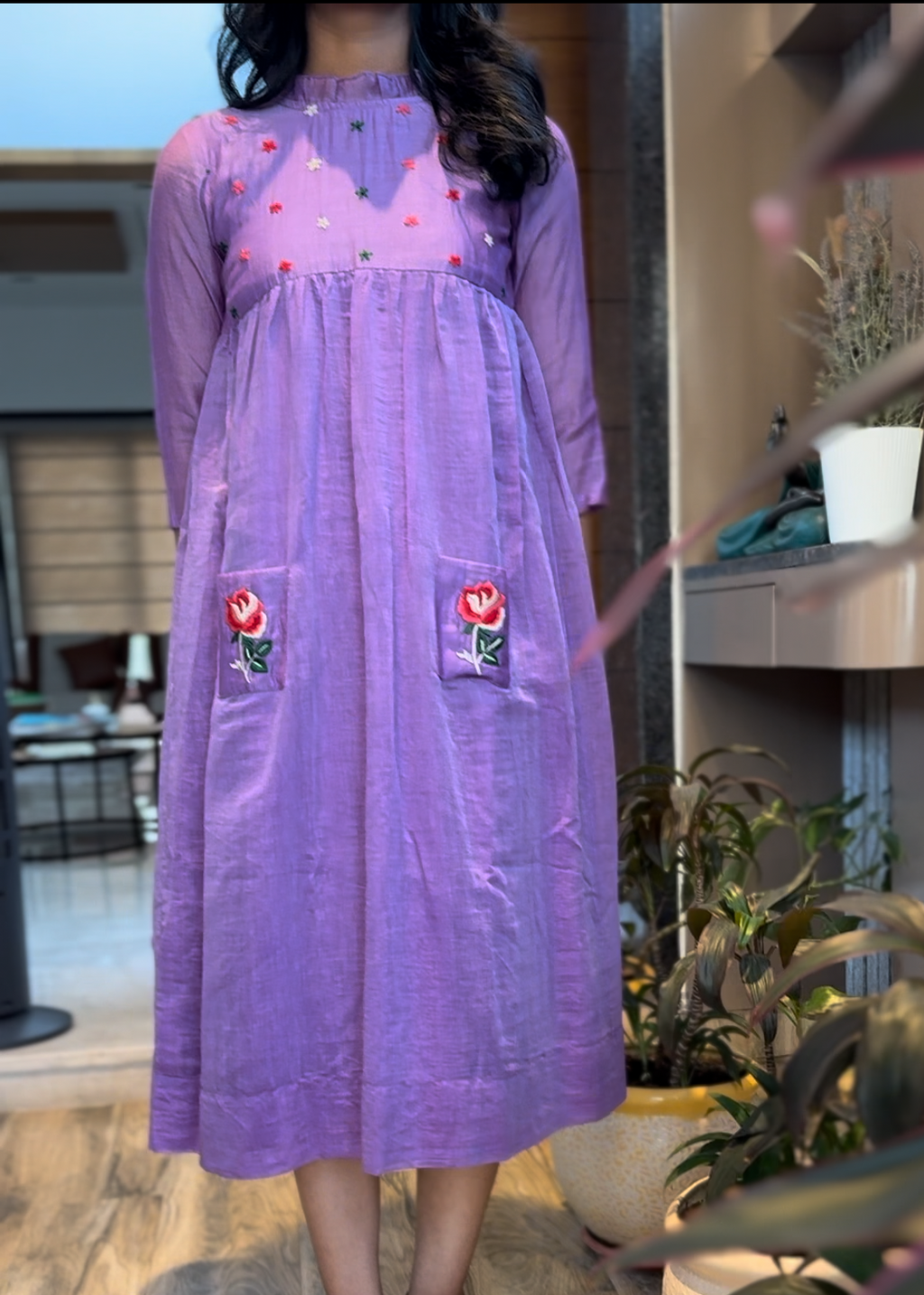 Person wearing a purple dress with floral patterns indoors.