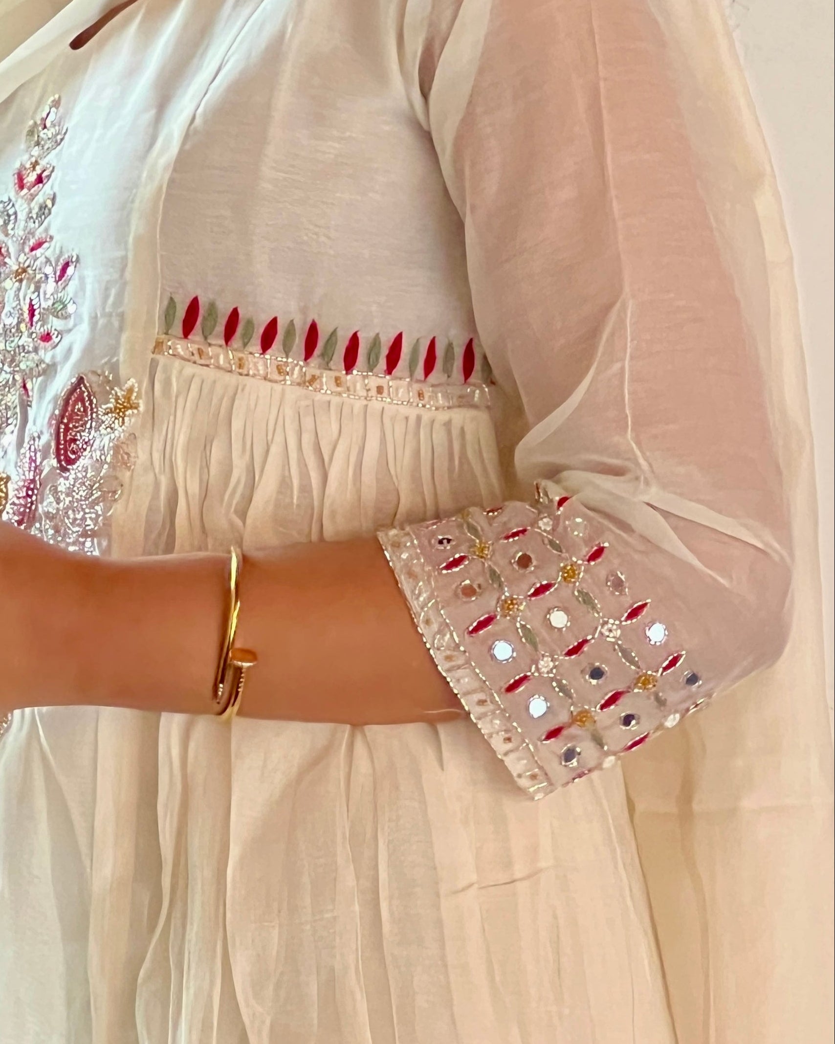 Person wearing a white embroidered outfit holding a green coconut.