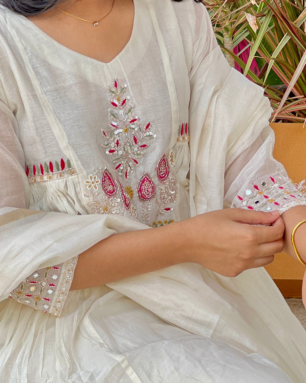 White embroidered traditional outfit with intricate patterns, worn by a person.