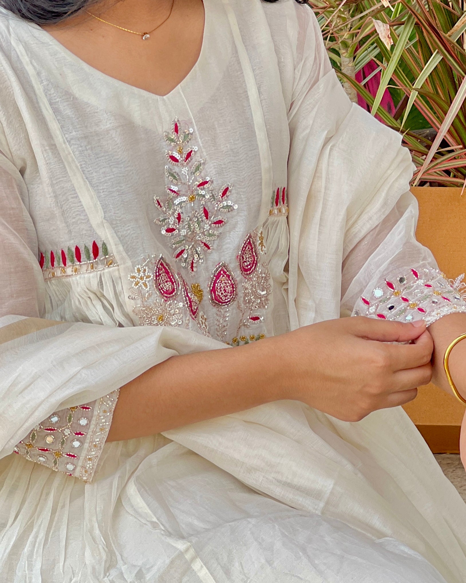 White embroidered traditional outfit with intricate patterns, worn by a person.