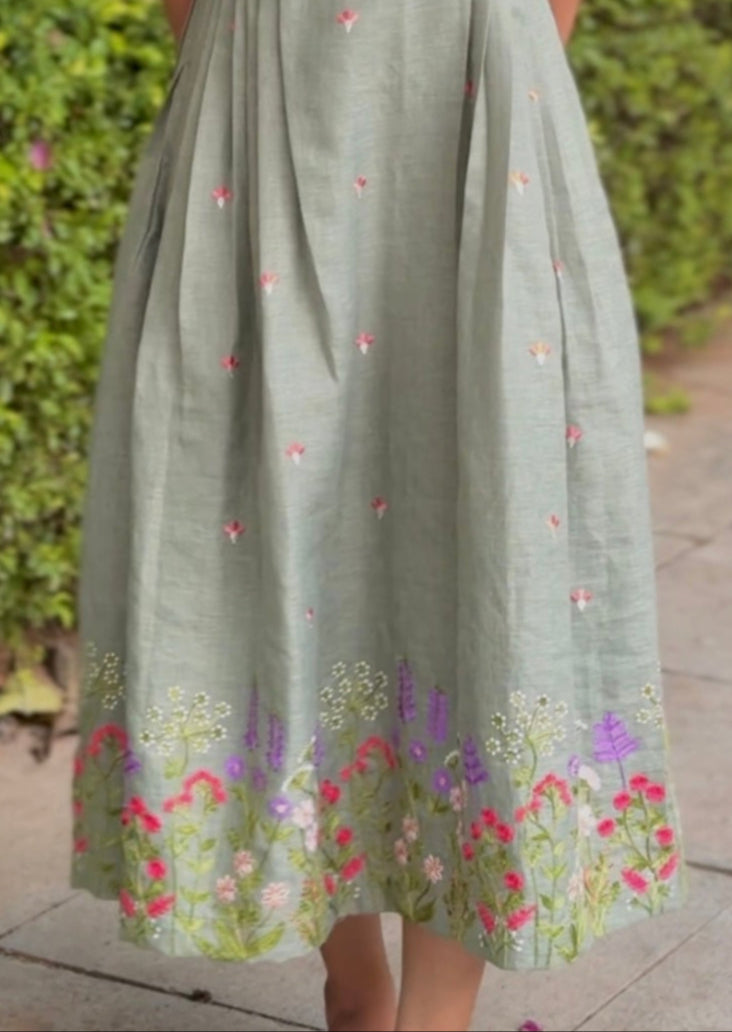 Woman wearing a light green dress with floral patterns standing outdoors.