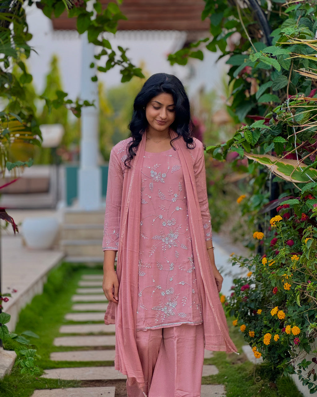 Woman in a pink traditional outfit standing in a garden