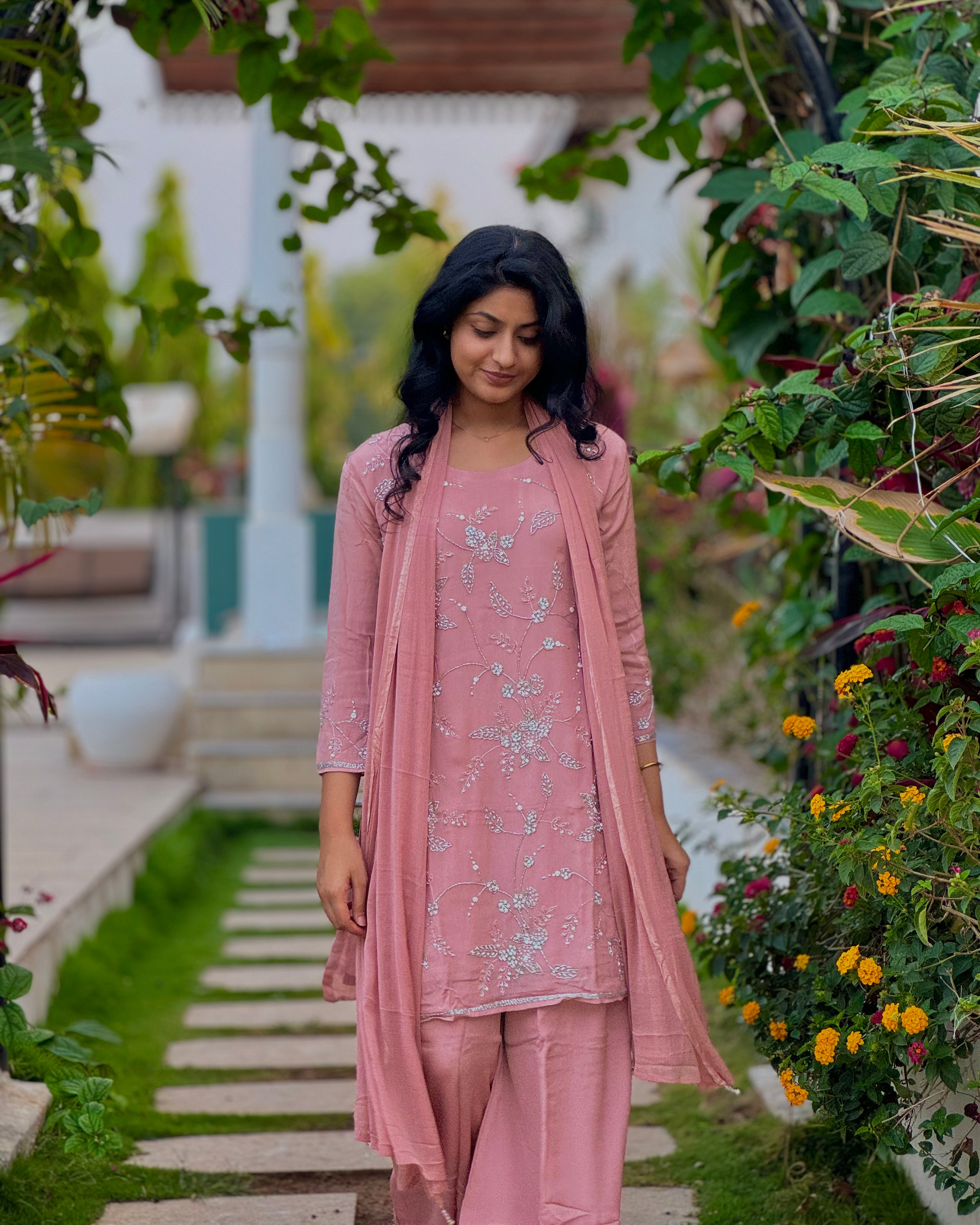 Woman in a pink traditional outfit standing in a garden