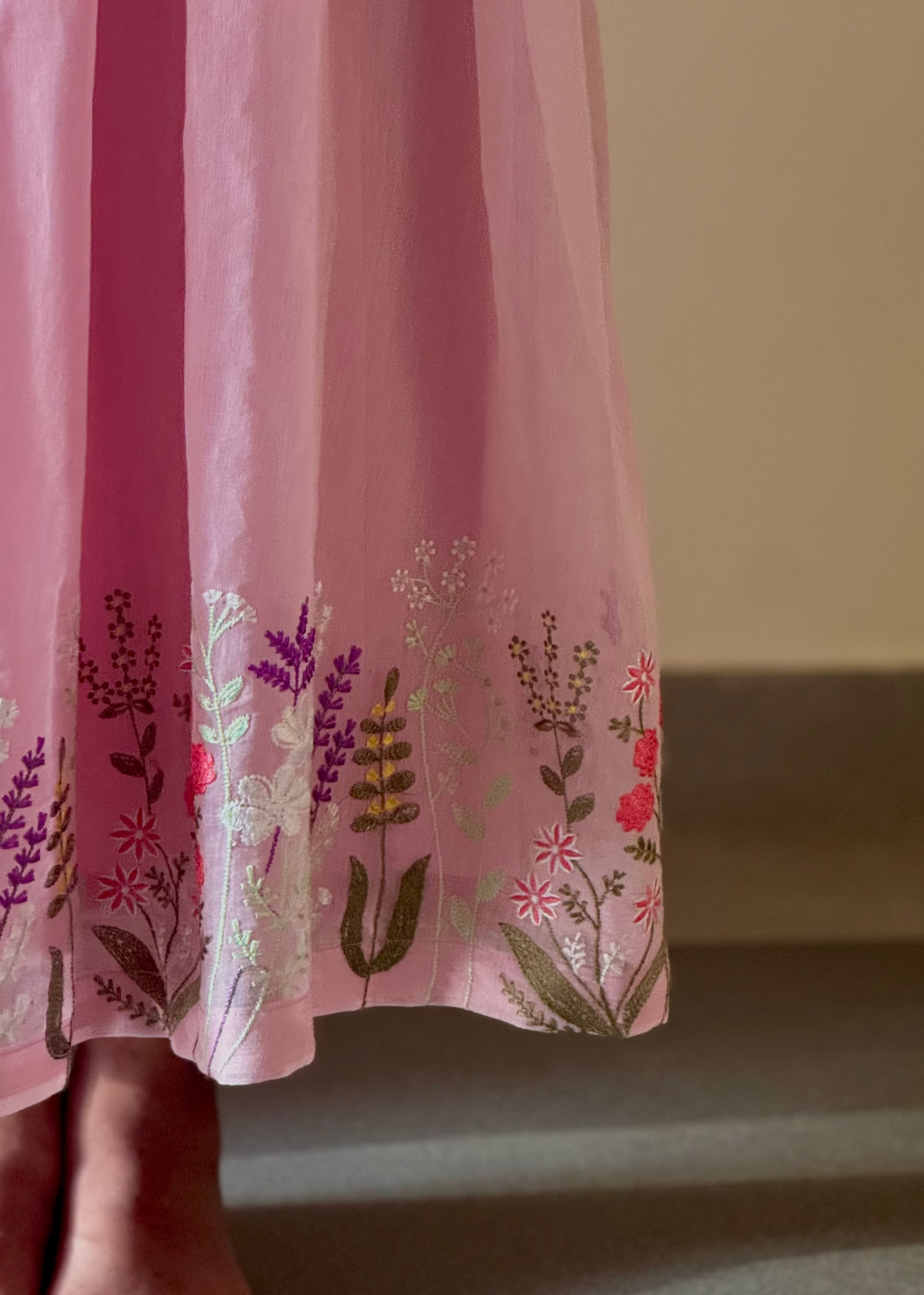Pink dress with floral embroidery on a plain background