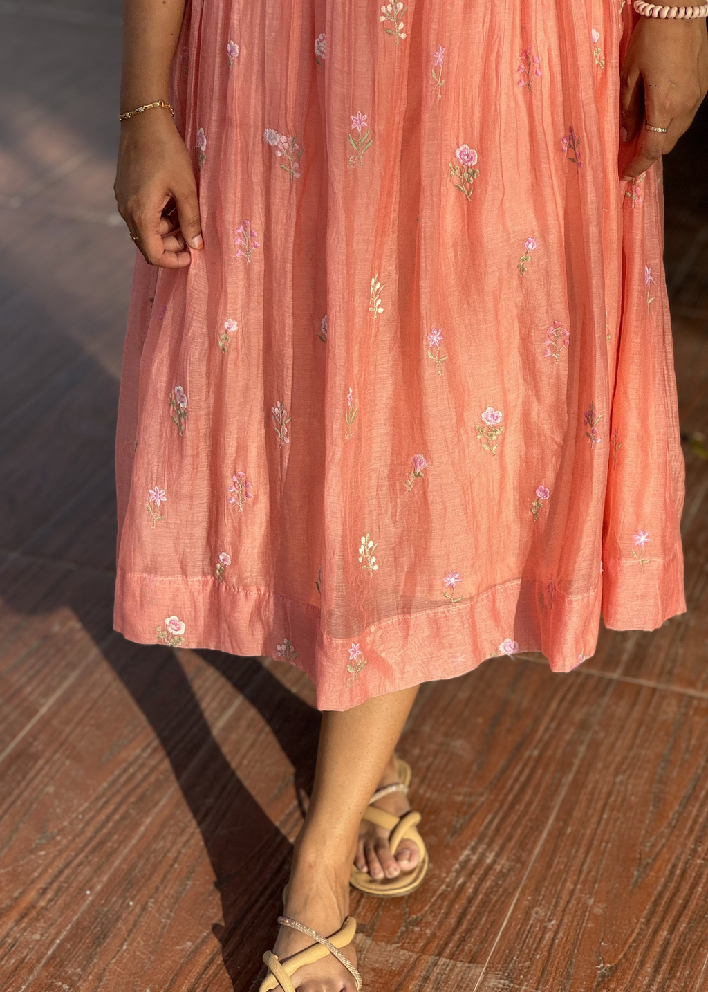 Person wearing a pink floral dress on a wooden floor