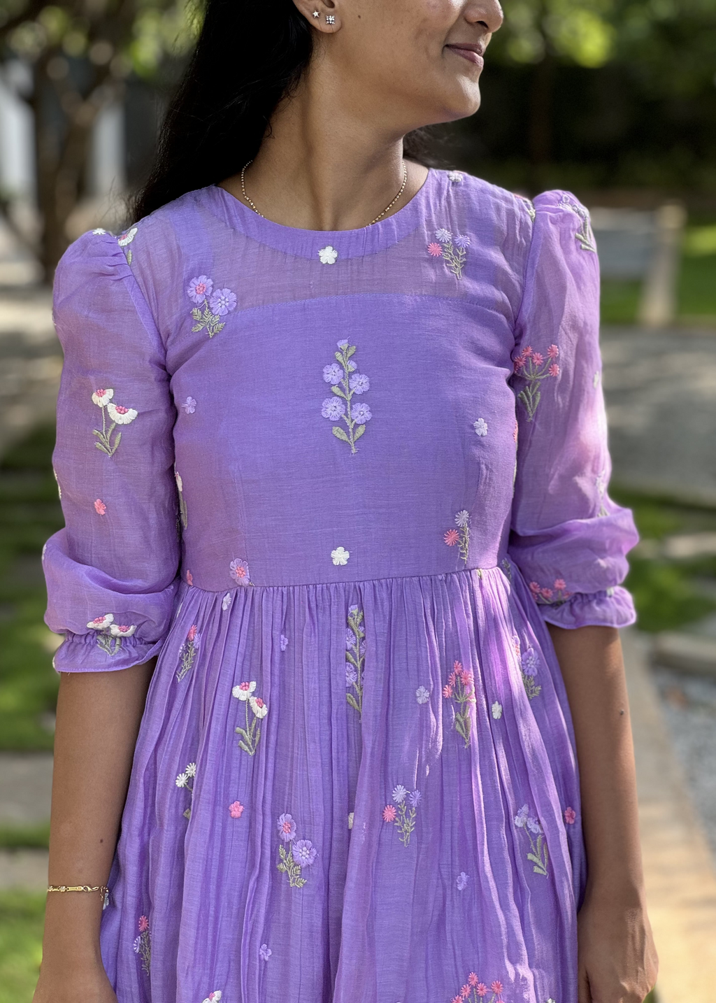 Woman wearing a purple dress with floral embroidery outdoors