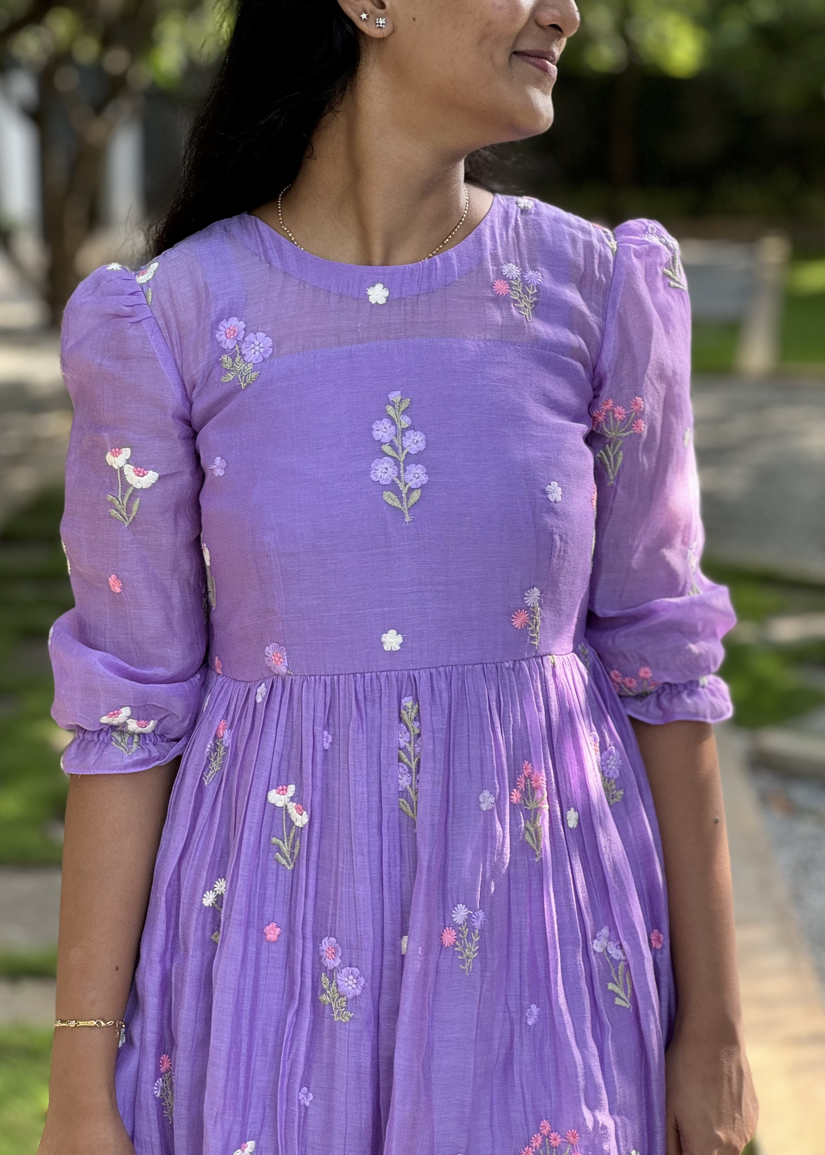 Woman wearing a purple dress with floral embroidery outdoors
