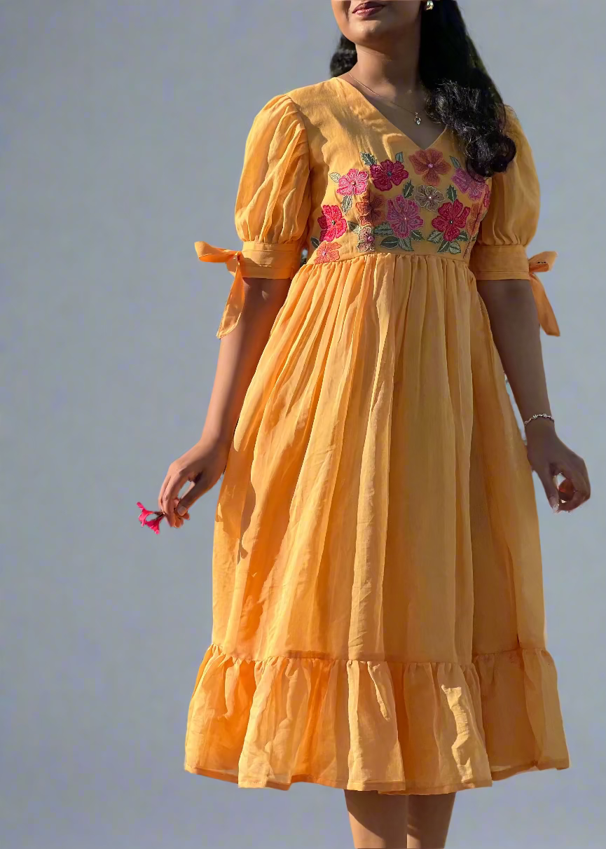 Woman wearing a yellow dress with floral embroidery outdoors